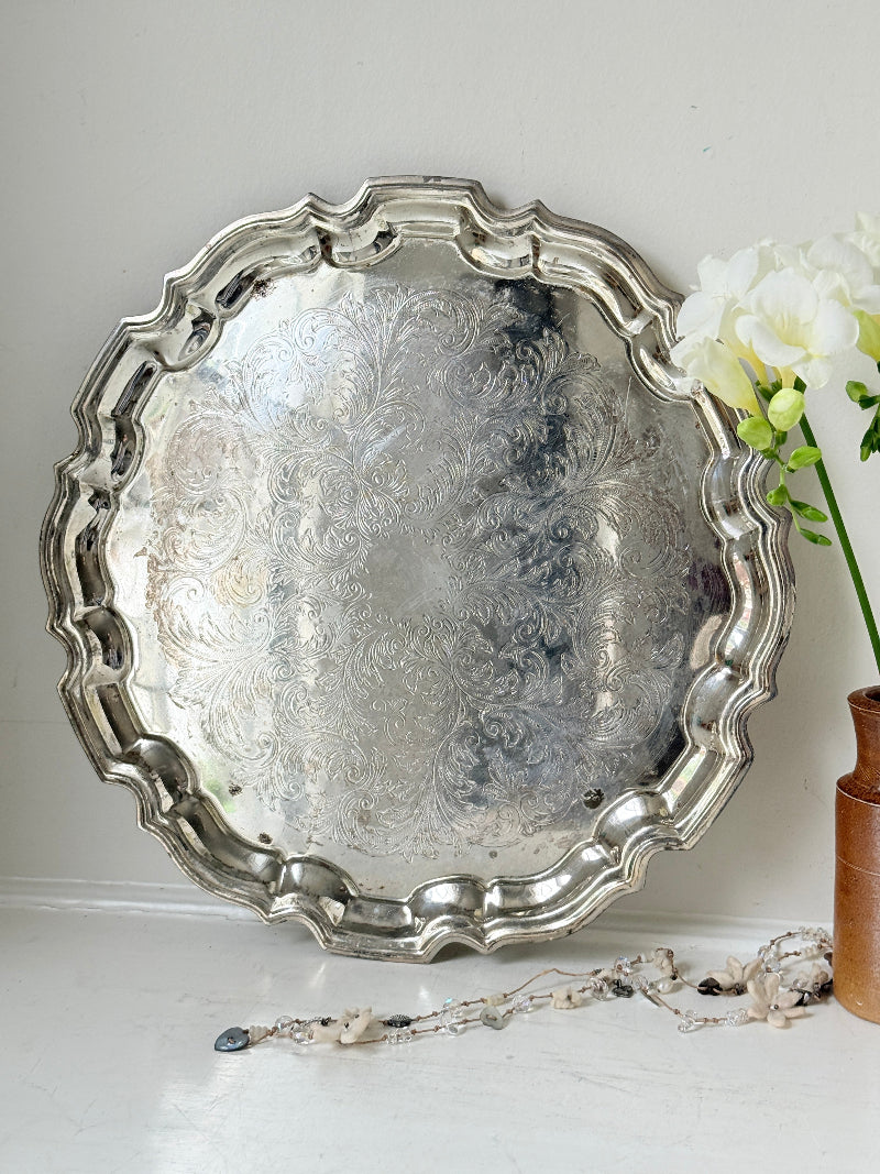 Vintage silver toned round serving tray with piecrust edge, aged patina and decorative scalloped rim for interior styling