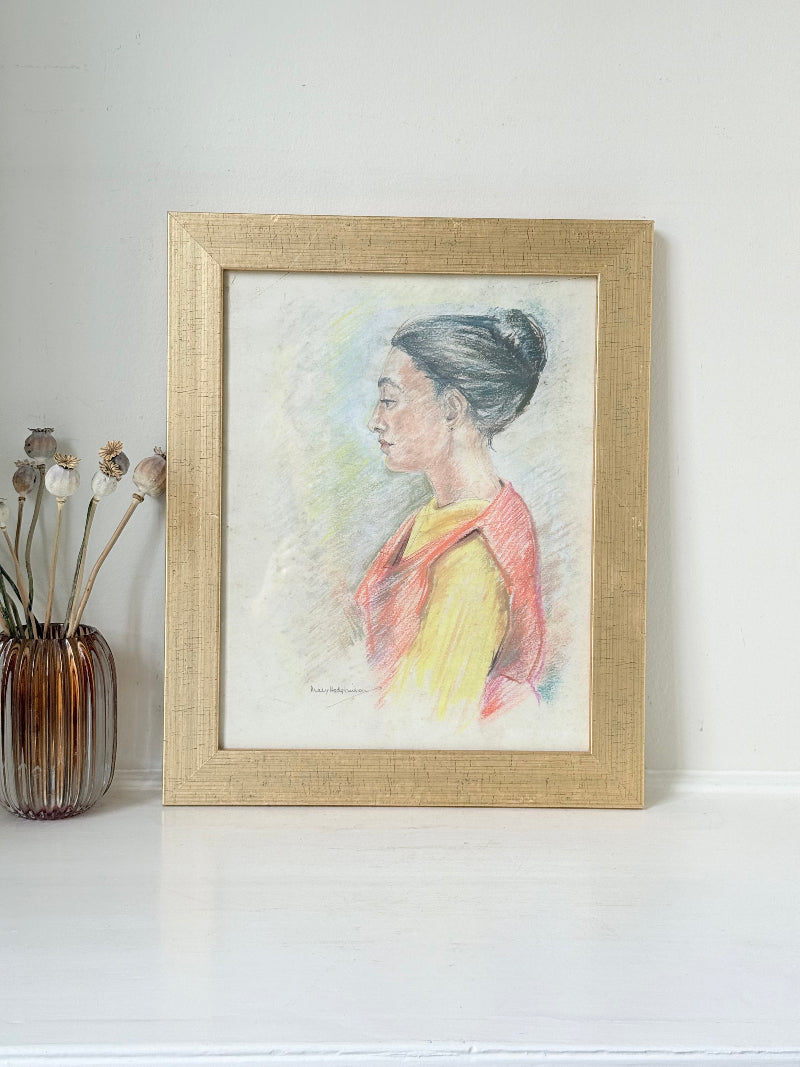 Vintage pastel portrait of a woman in profile wearing red and yellow, framed under glass, photographed on a white surface