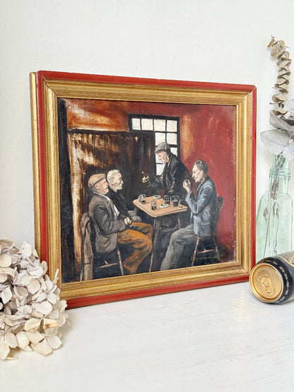A framed oil painting depicting three men in suits sitting around a table, displayed on a white surface with dried flowers and decorative props.