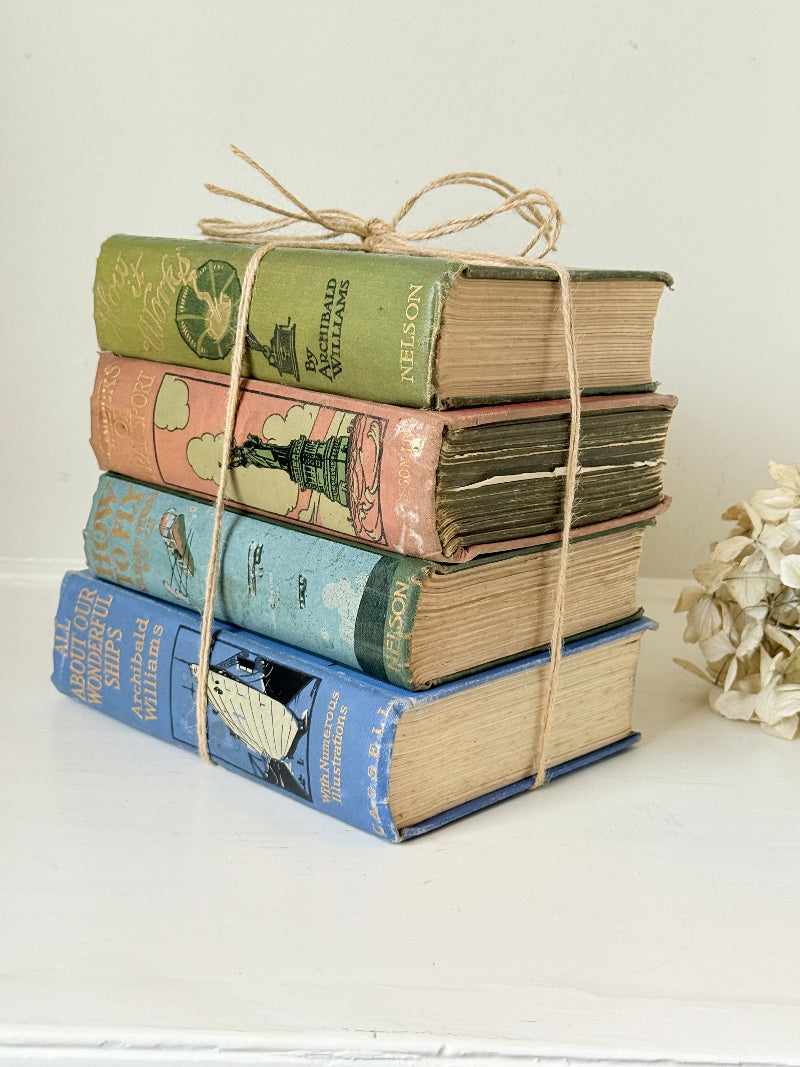 Vintage decorative book bundle in green, blue, and coral with printed lettering, tied with twine, photographed on a white surface