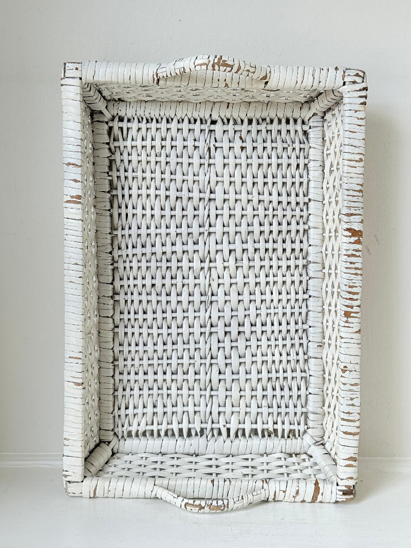 Vintage white painted wicker tray with woven handles photographed on a white surface