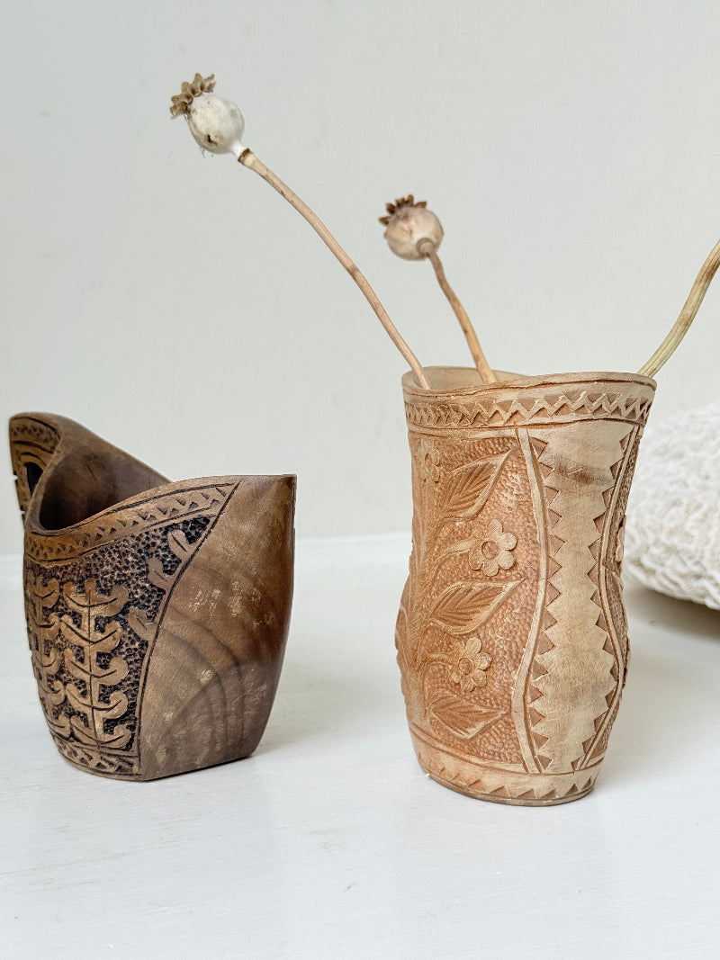 Pair of hand carved wooden jug and vase in contrasting light and dark tones, styled with dried poppy heads on a white surface.