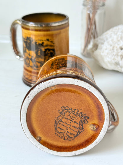 Pair of Ridgways stoneware tankard mugs photographed on a white surface in amber brown glaze with black Coaching Days and Coaching Ways transfer scenes