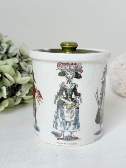 vintage Holkham pottery condiment pot with green lid and illustrated figures photographed on white surface
