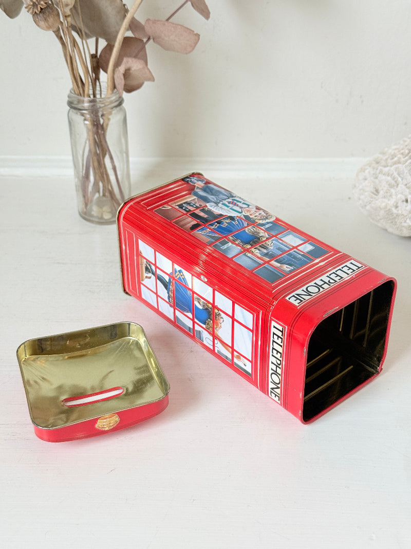 Vintage red telephone box tin money box on a white surface