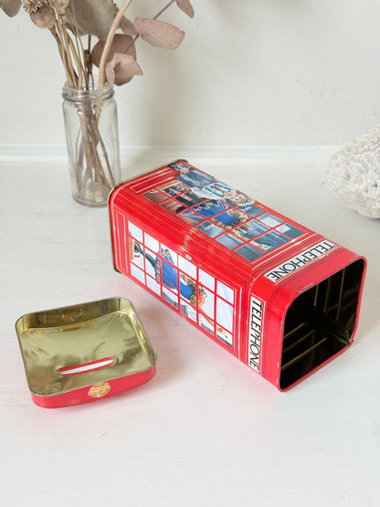Vintage red telephone box tin money box on a white surface