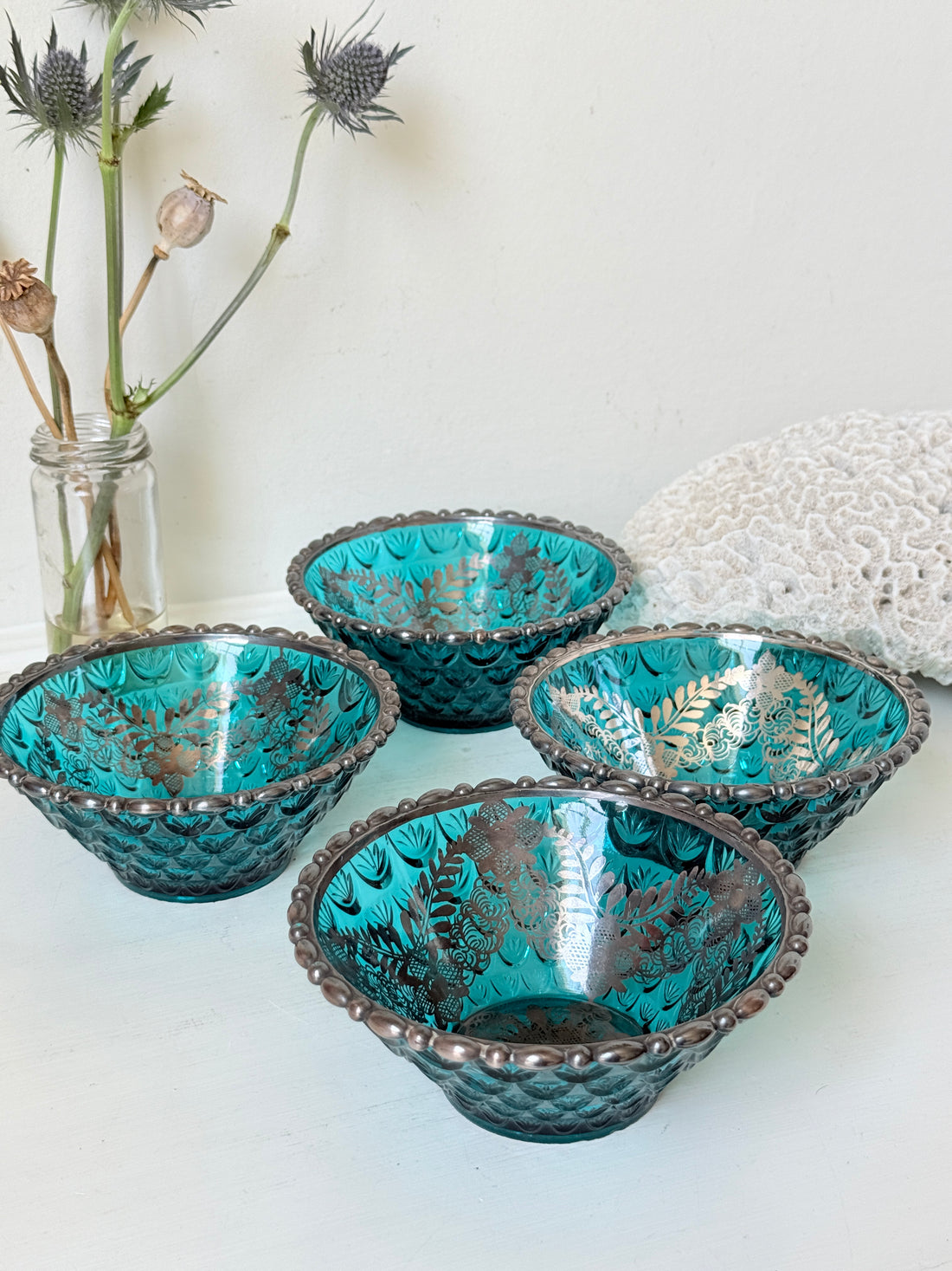 Set of four vintage teal pressed glass dessert bowls with gilt floral decoration, photographed on a white surface