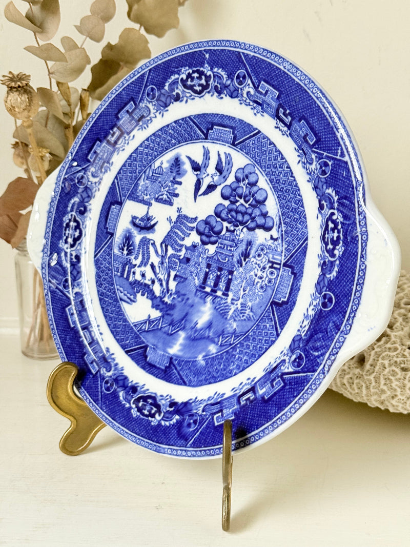 Blue Willow serving plate with scroll handled relief shown on a white surface.