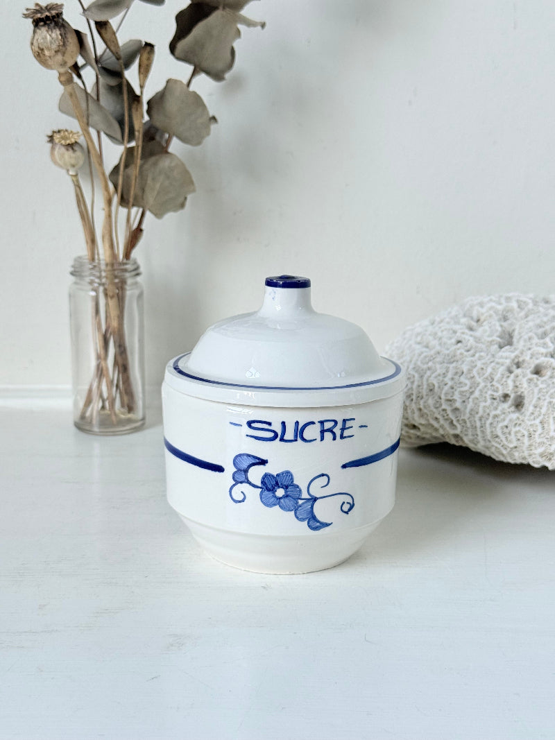 Vintage French blue and white studio pottery sugar bowl with lid, photographed on a white surface.