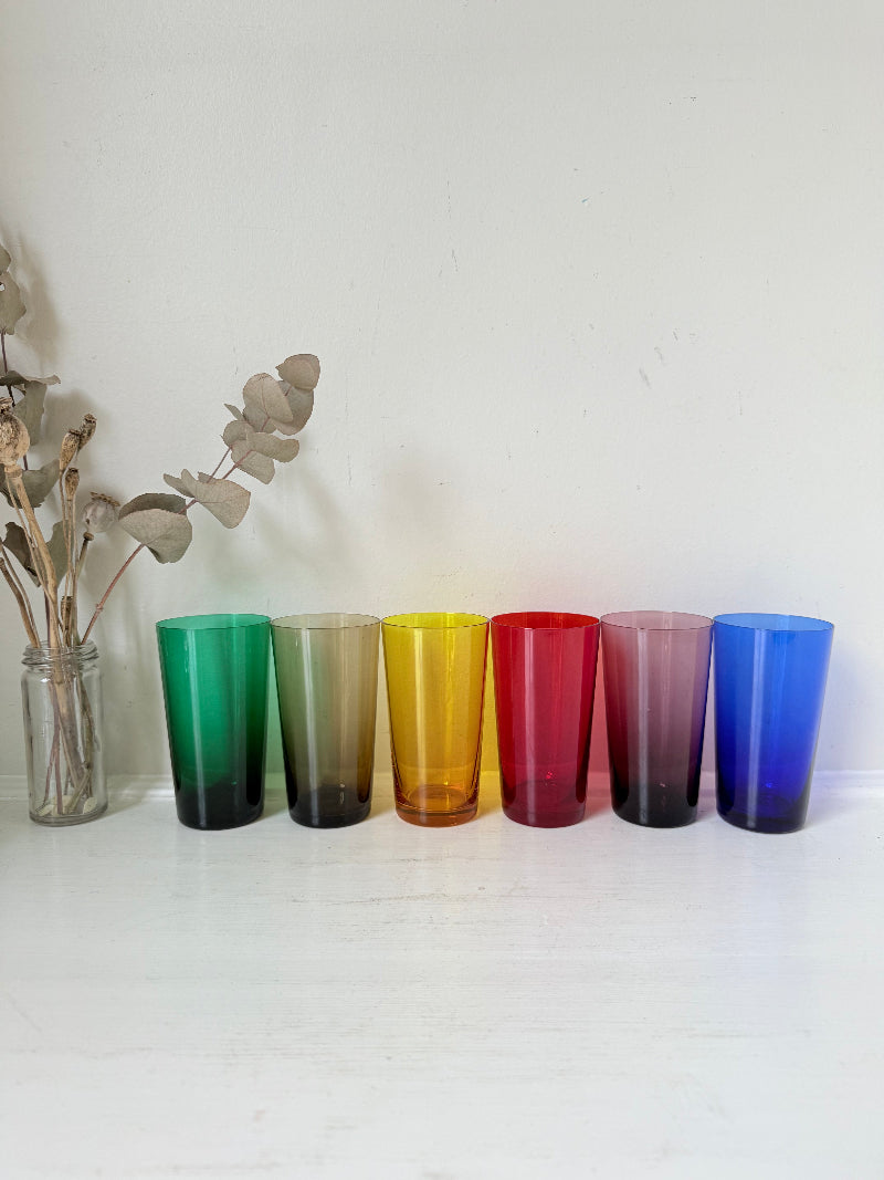 Set of six mid-20th century Boussu coloured glass tumblers in green, yellow, red, violet, blue and brown, photographed on white surface.