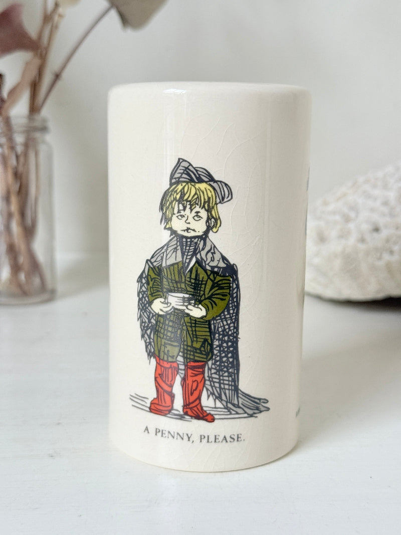 Vintage ceramic money box with illustrated figures photographed on a white surface