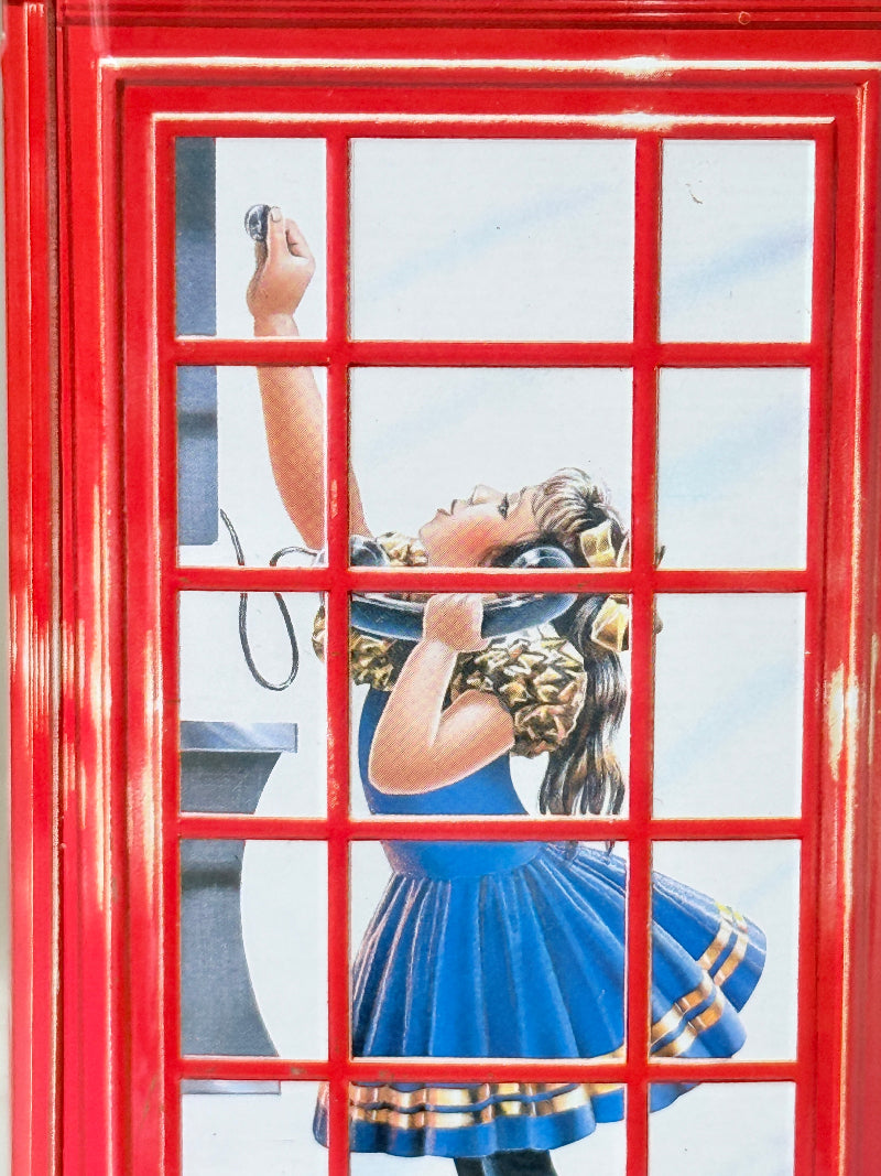 Vintage red telephone box tin money box on a white surface