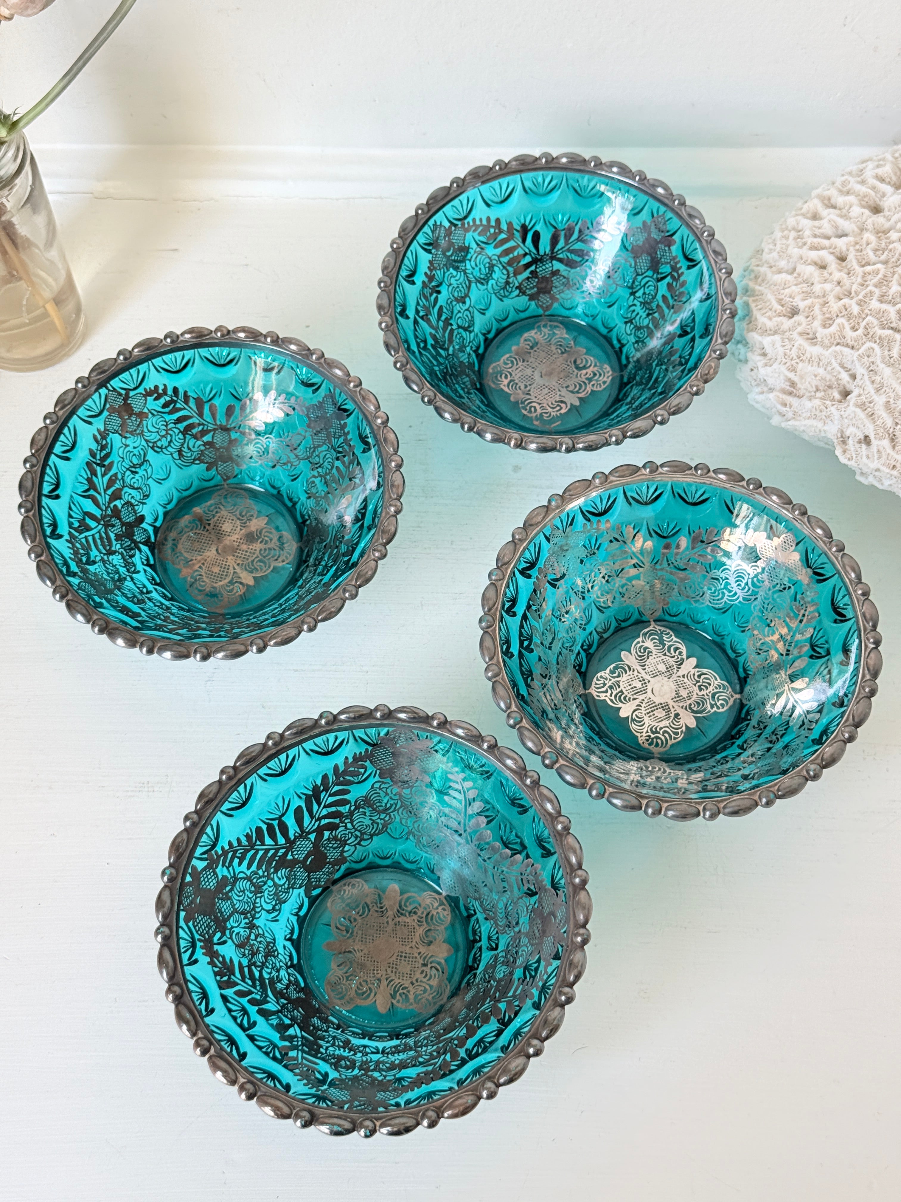 Set of four vintage teal pressed glass dessert bowls with gilt floral decoration, photographed on a white surface