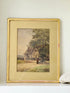 Antique framed watercolour of English village street with thatched cottages and figures, in gilt frame with wide mount, on white surface.