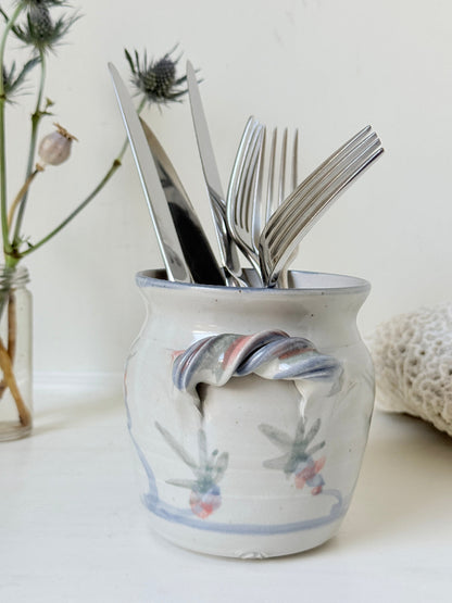 Vintage studio pottery utensil pot with hand painted floral decoration and applied handle detail, photographed on a white surface