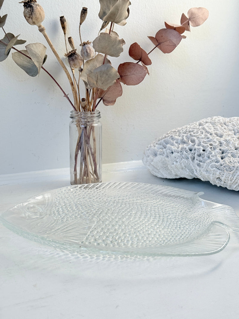 Vintage clear glass fish shaped serving dish with textured scale pattern photographed on a white surface