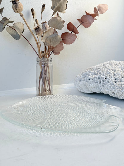 Vintage clear glass fish shaped serving dish with textured scale pattern photographed on a white surface