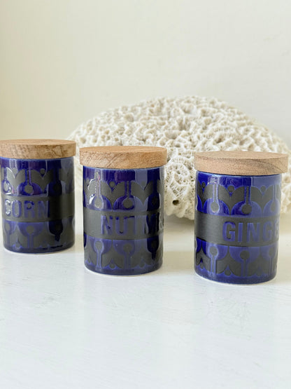 Set of three Hornsea Pottery spice jars in cobalt blue with wooden lids, labelled Ginger, Nutmeg, and Peppercorn, photographed on white surface

