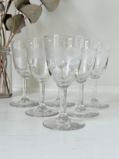 Set of six vintage etched clear glasses with decorative banding, one with a tiny rim chip, photographed on white surface.