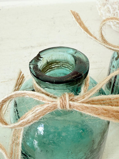 Set of antique green glass ink bottles with rounded forms, photographed on white surface.