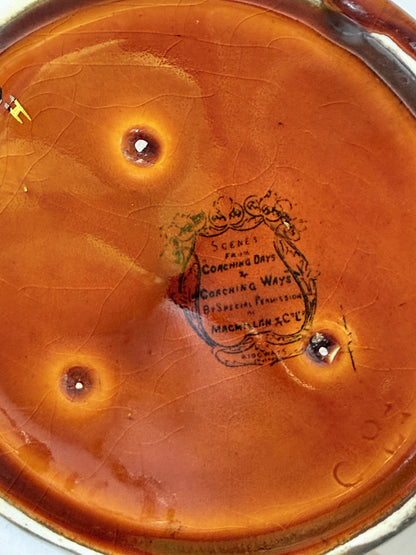 Antique Ridgways stoneware jug photographed on a white surface in amber treacle glaze with black Coaching Days and Coaching Ways scenes and silver lustre rim