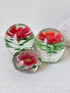 Trio of vintage glass paperweights with hand worked red floral detail, clear glass domes and green leaf decoration