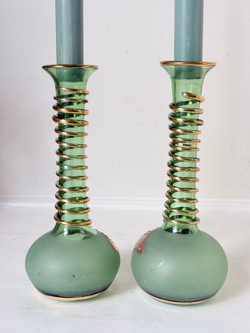 Pair of vintage green glass candlesticks with gold detail and spiral stems styled with blue taper candles on white surface