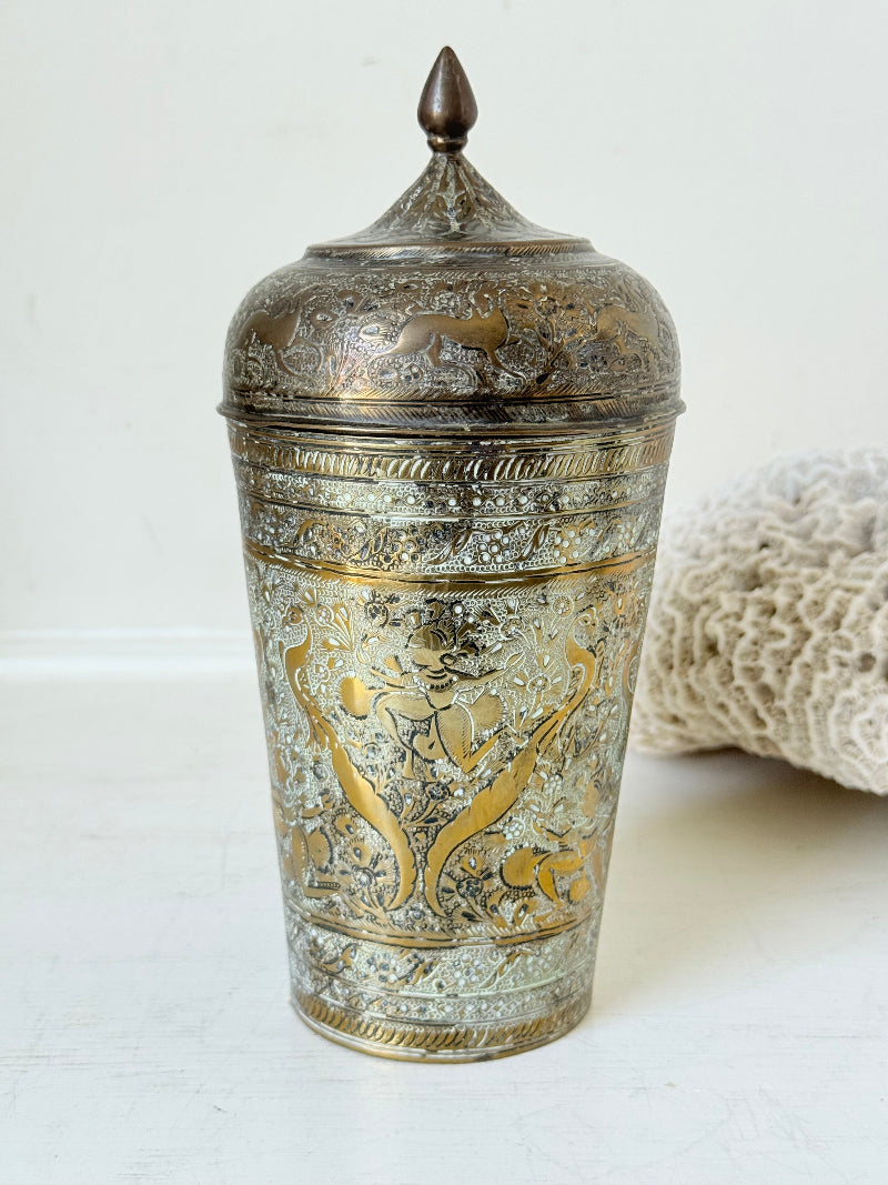 Indian Benares brass jar with lid and engraved animals and floral design, photographed on a white surface