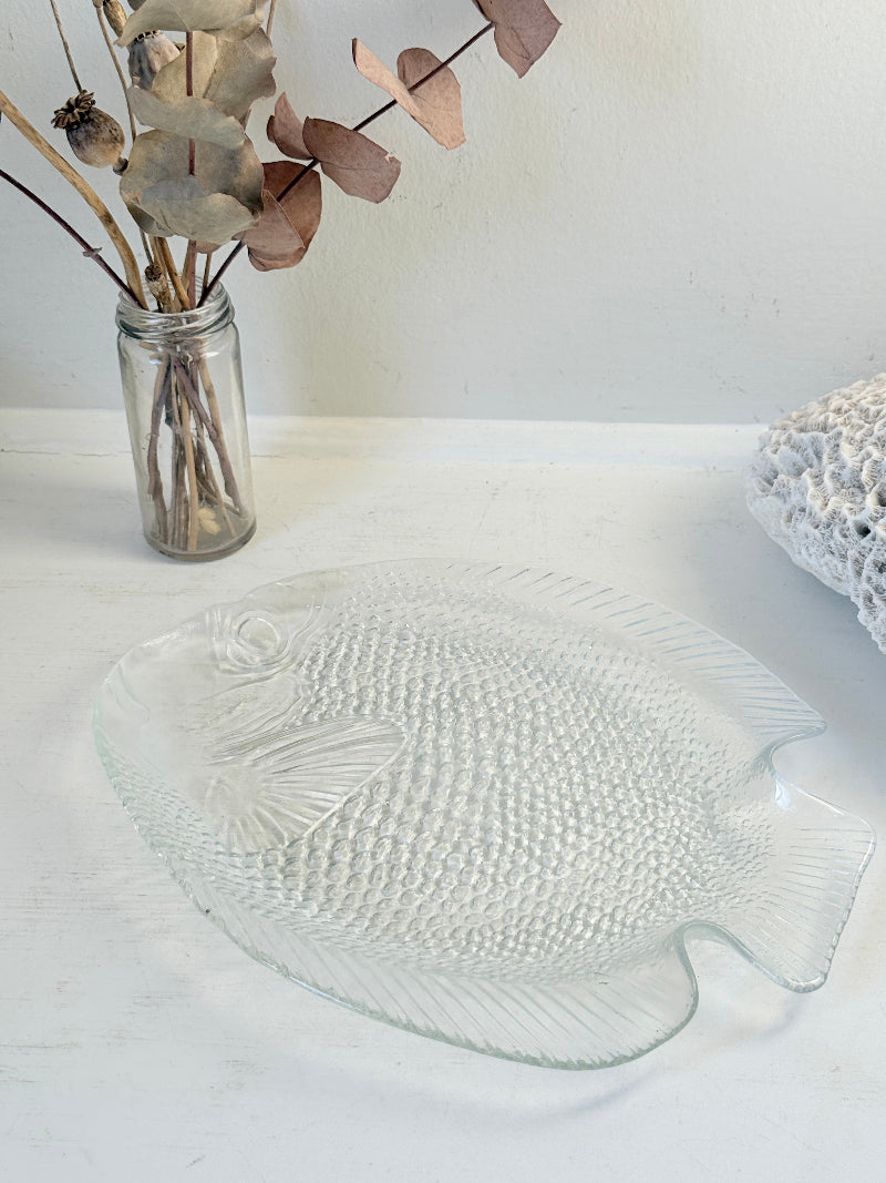 Vintage clear glass fish shaped serving dish with textured scale pattern photographed on a white surface