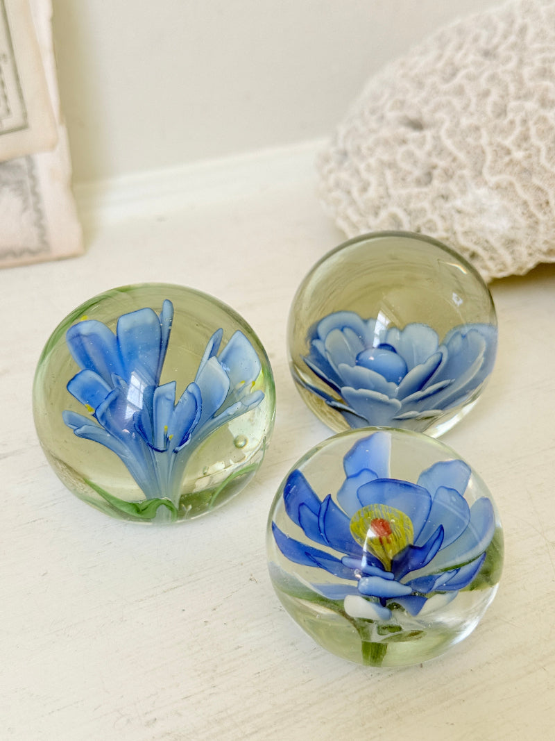 Trio of vintage glass paperweights with hand worked blue floral detail, clear glass domes and green leaf decoration