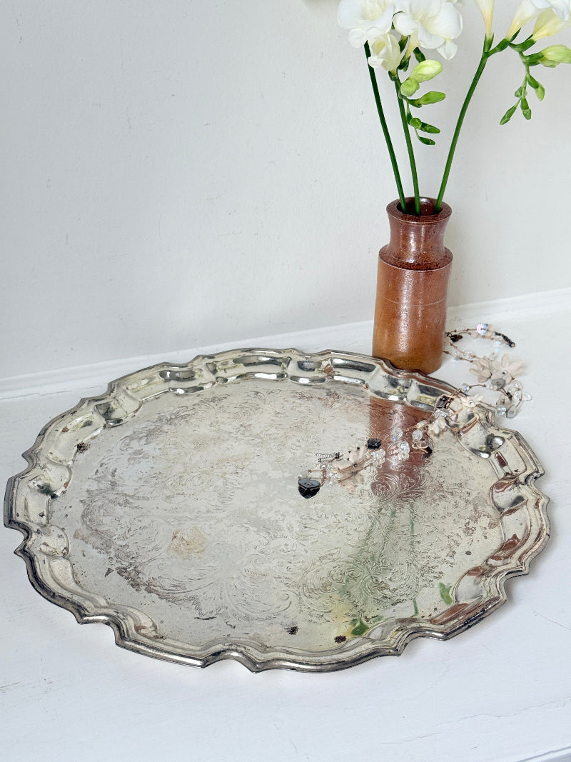 Vintage silver toned round serving tray with piecrust edge, aged patina and decorative scalloped rim for interior styling