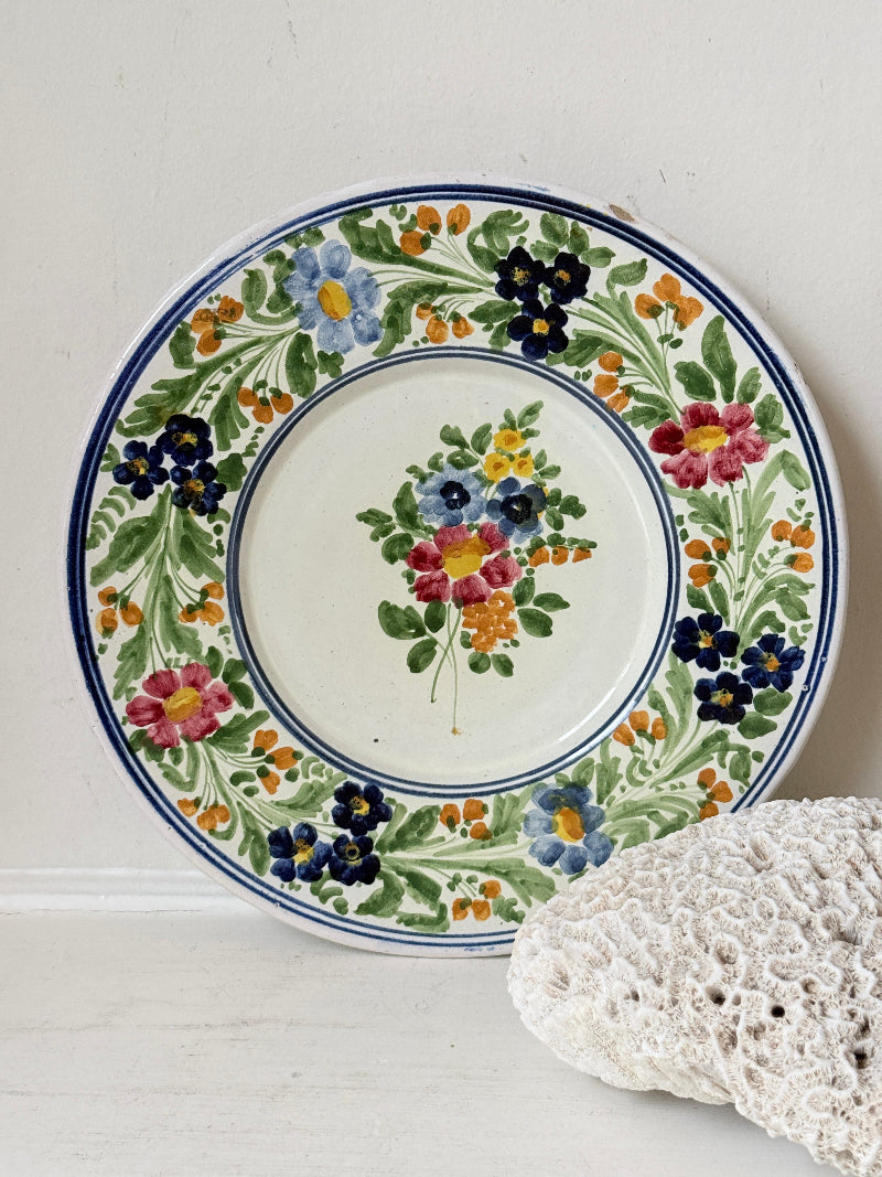 Vintage Italian majolica floral plate with blue green yellow and pink decoration photographed on a white surface
