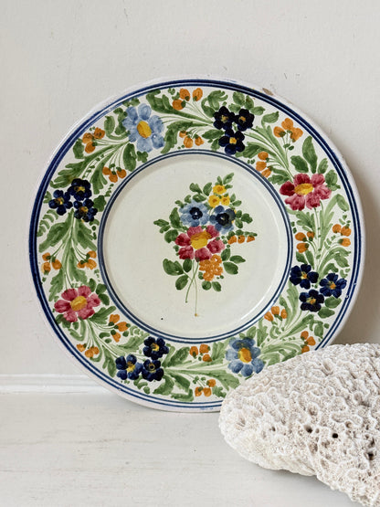 Vintage Italian majolica floral plate with blue green yellow and pink decoration photographed on a white surface