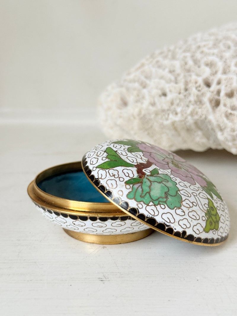 Vintage brass and enamel cloisonne trinket box with floral lid and turquoise interior photographed on a white surface