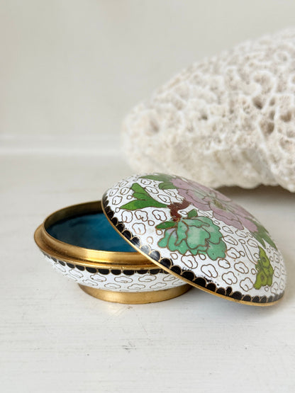 Vintage brass and enamel cloisonne trinket box with floral lid and turquoise interior photographed on a white surface