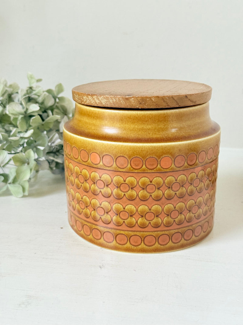 Vintage Hornsea kitchen canister in Saffron yellow with wooden lid photographed on a white surface.