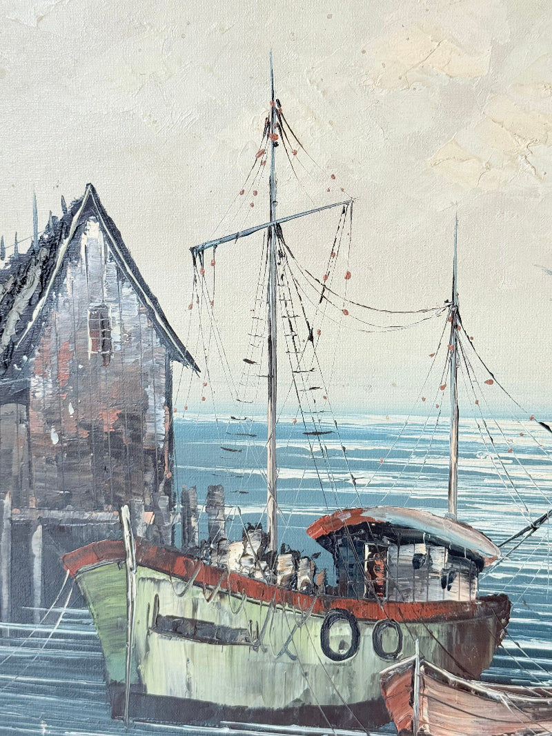 Vintage harbour scene oil painting of fishing boat and wharf buildings in gilt frame, textured brushwork, on white surface.