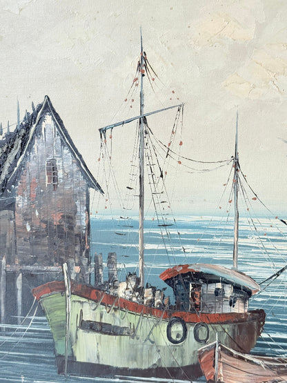 Vintage harbour scene oil painting of fishing boat and wharf buildings in gilt frame, textured brushwork, on white surface.