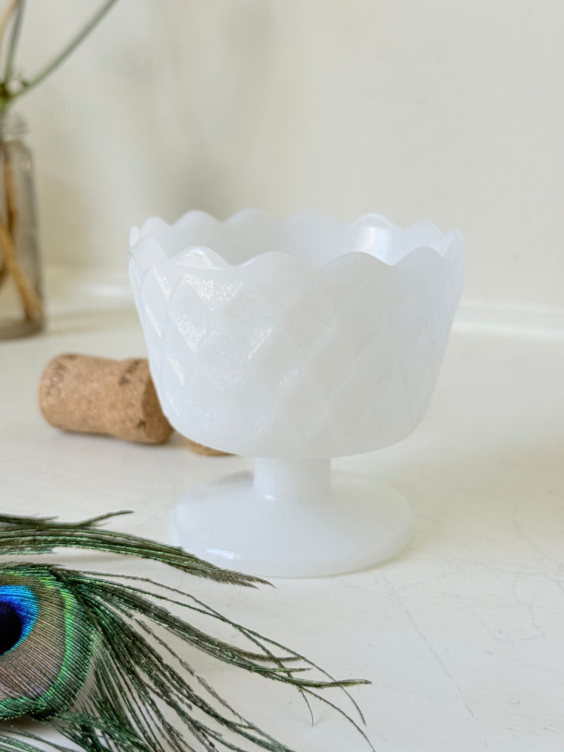 Vintage milk glass footed bowl with scalloped rim and pressed pattern, photographed on a white surface