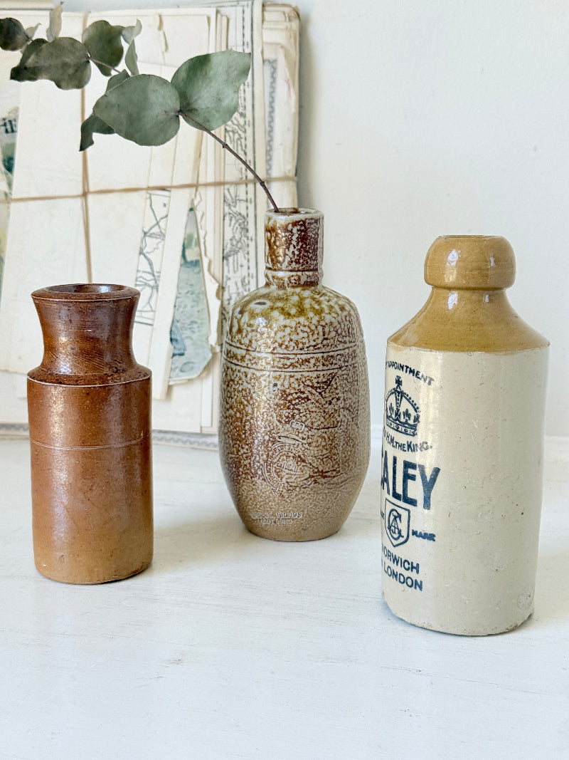 Three antique stoneware bottles, a printed Caley of Norwich and a Portuguese Campos Filhos, photographed on a white surface