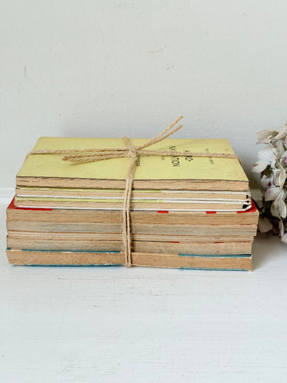 Bundle of vintage Penguin paperback books in orange and cream tones tied with twine, photographed on a white surface