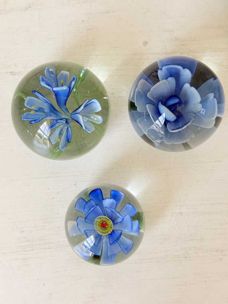Trio of vintage glass paperweights with hand worked blue floral detail, clear glass domes and green leaf decoration