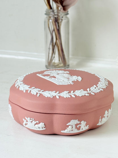 Rare vintage Wedgwood Jasperware round lidded trinket box in terracotta rose pink, with a central classical cameo scene and white laurel wreath border.