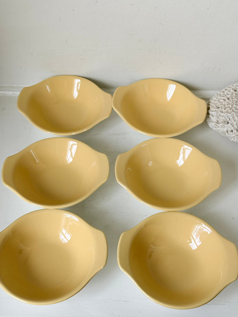 Set of six vintage Poole Pottery lemon bowls in butter yellow glaze photographed on a white surface