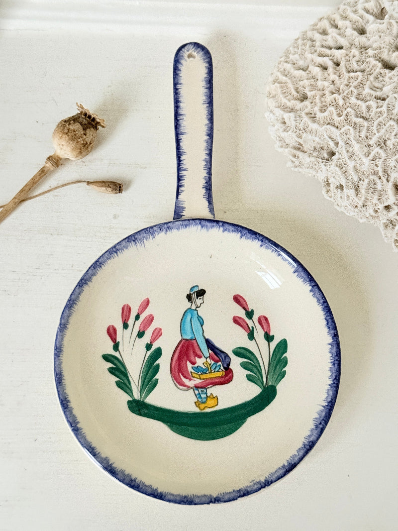 French Quimper faience handled wall dish with Petit Breton figure and blue rim, photographed on a white surface