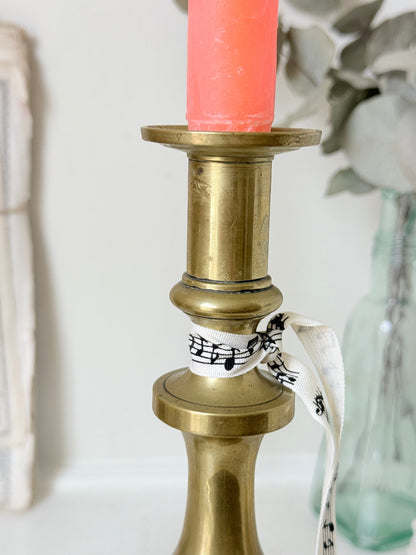 Pair of antique brass candlesticks with turned baluster stems and stepped bases holding coral tapers