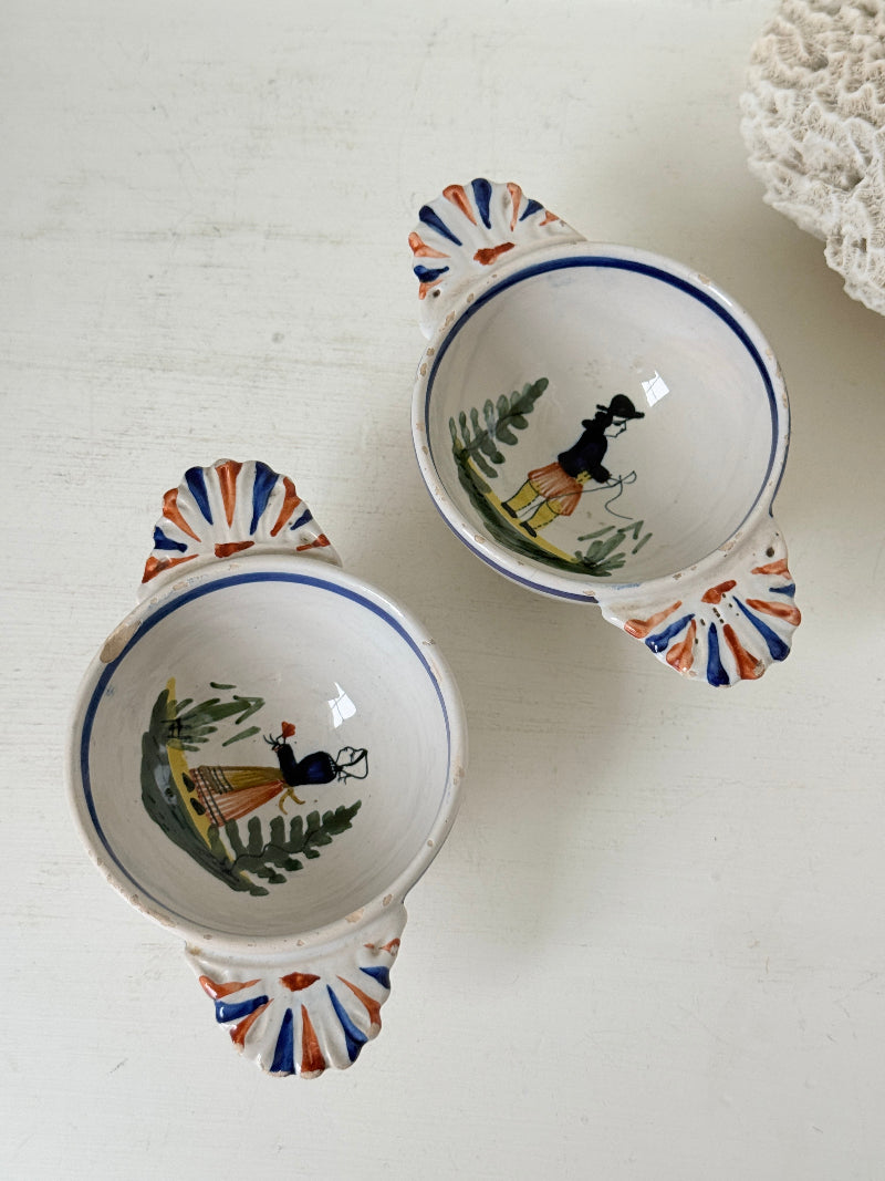 Pair of vintage French Quimper olive bowls with Breton figure and fan handles, photographed on a white surface