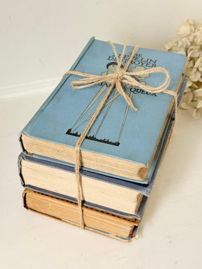 Vintage decorative book bundle in blue and ochre tied with twine, photographed on a white surface