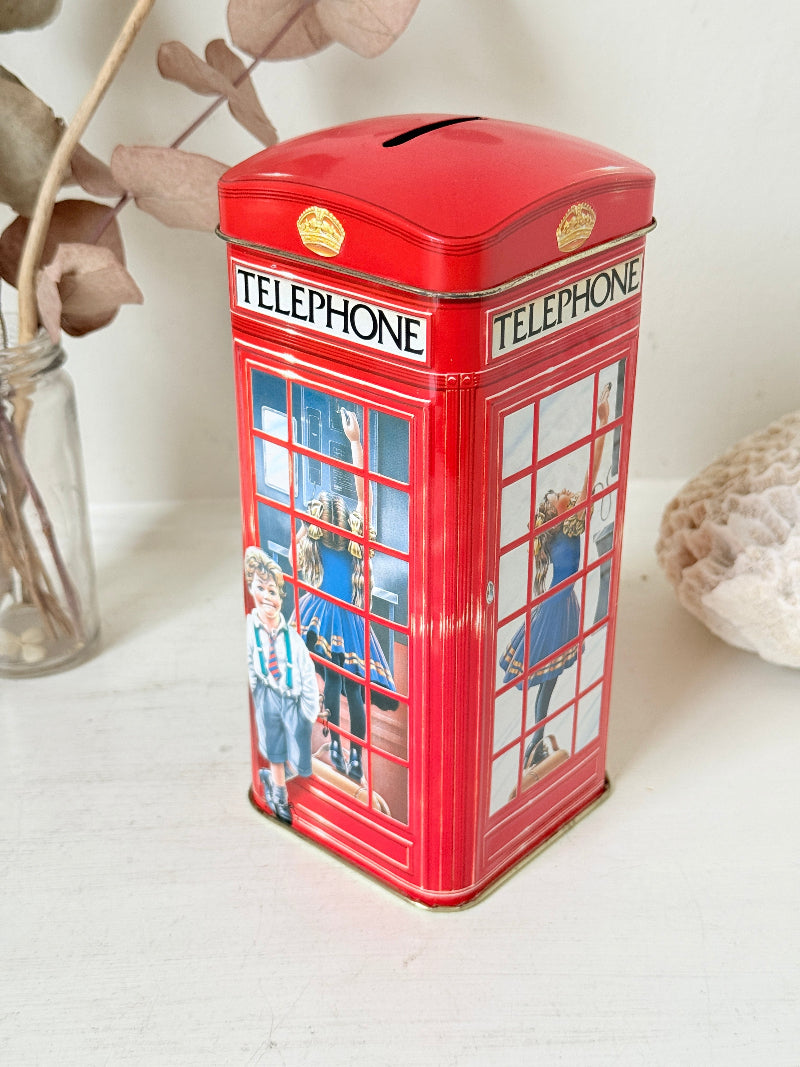 Vintage red telephone box tin money box on a white surface