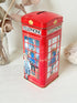 Vintage red telephone box tin money box on a white surface